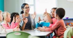 Teacher surrounded by children in school.
