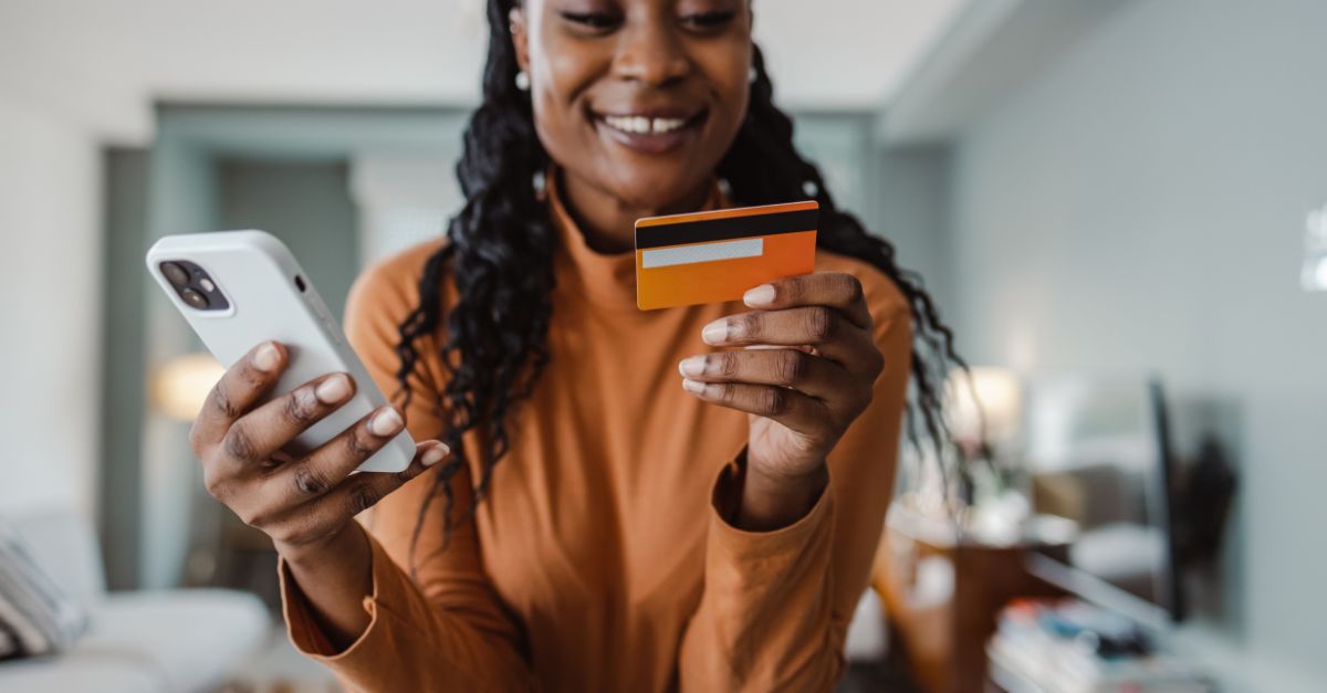 Happy lady holding her mobile phone while reading card information.
