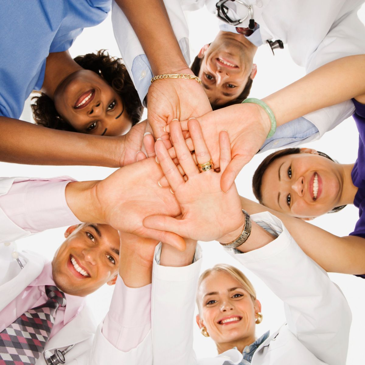 Portrait of healthcare workers looking down with hands united.